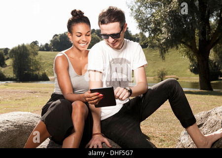 Jeune couple using digital tablet in park Banque D'Images