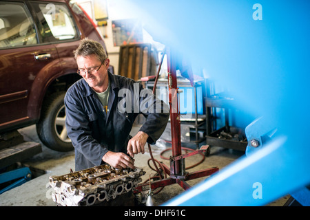 Mécanicien travaillant sur des pièces de voiture dans garage Banque D'Images