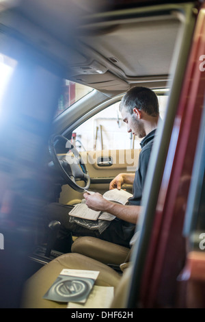 Mécanicien assis dans le siège du conducteur de voiture avec entretien Banque D'Images