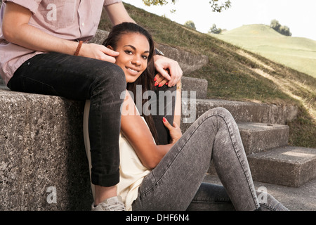 Young couple sitting on steps in park Banque D'Images