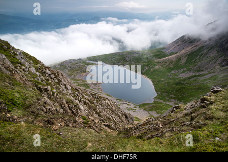 À la recherche du haut de la montagne Cadair Idris dans le parc national de Snowdonia sur Llyn y Gader avec stormy nuageux ciel d'été. Banque D'Images