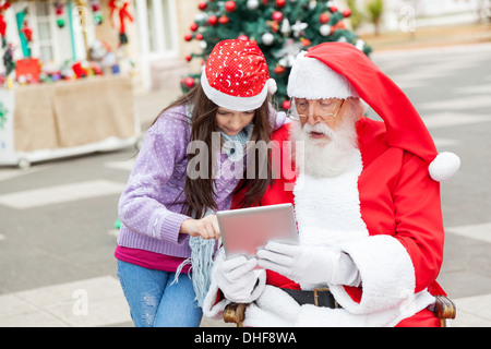 Fille et Père Noël Using Digital Tablet Banque D'Images