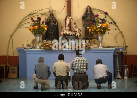 Les hommes prient comme ils s'agenouillent devant un autel pendant le Jour des Morts au cimetière Teotilan del Valle, à Oaxaca, Mexique Banque D'Images