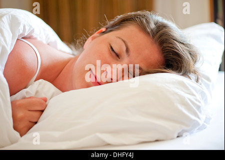 Femme dort sur un lit blanc comme neige le matin Banque D'Images