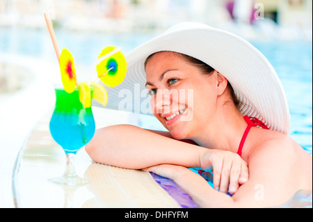 Belle femme en appui sur le bord de la piscine Banque D'Images