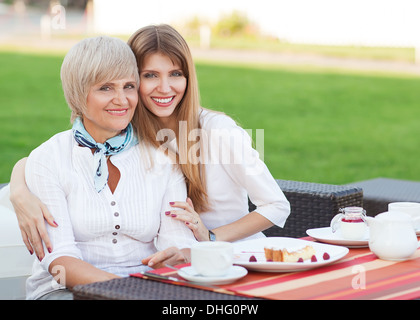 Mère et fille adultes de boire du thé ou du café et talking outdoors Banque D'Images
