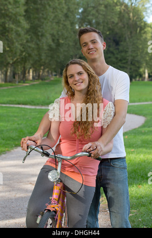 Jeune couple avec leur vélo sur un chemin dans un parc Banque D'Images