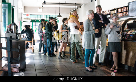 Bien soigné avec désinvolture les New-yorkais à attendre en ligne pour commander un café au Starbucks de l'upper west side de Manhattan samedi automne chaud Banque D'Images