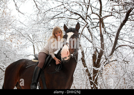 La sérénité jeune fille à cheval sur un cheval en hiver woods au matin de Noël Banque D'Images