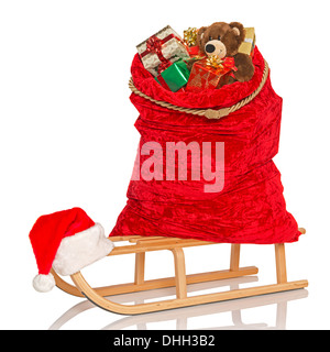 Santa's sac plein de gift wrapped Christmas presents et jouets sur un traîneau en bois, isolé sur un fond blanc. Banque D'Images