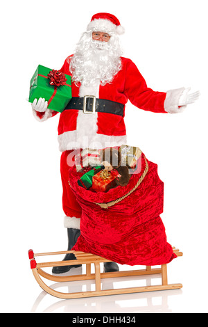 Le Père Noël avec un sac rempli de jouets et cadeaux enveloppés présente sur un traîneau, isolé sur un fond blanc. Banque D'Images