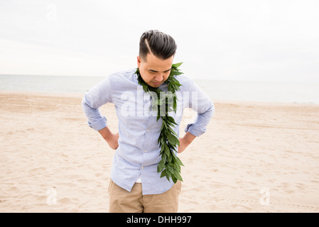 Homme debout sur la plage avec le feuillage autour du cou