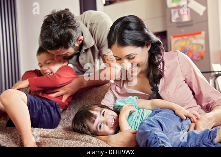 Famille avec deux enfants jouant sur canapé Banque D'Images