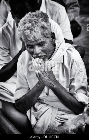 Ancien indien dans la prière dans l'attente à Sri Sathya Sai Baba l'hôpital mobile. L'Andhra Pradesh, Inde. Noir et blanc. Banque D'Images