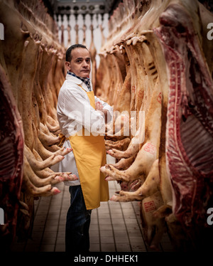 Portrait de boucher italien entouré par pendaison des carcasses de porc Banque D'Images