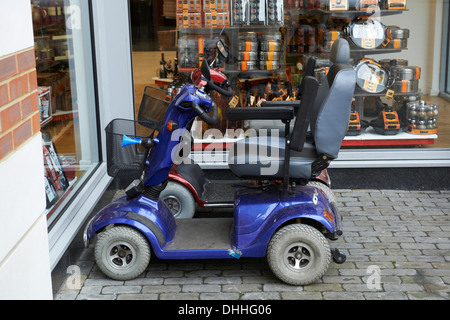 Fauteuil motorisé stationné à côté d'une boutique à Canterbury, Kent Banque D'Images