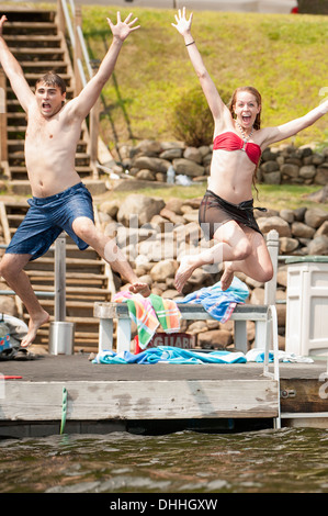 Jeune couple de sauter dans le lac Banque D'Images