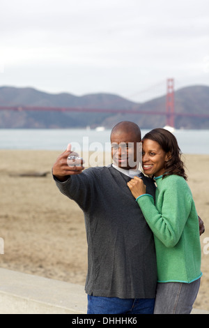 Happy black couple prend un portrait selfies en face du Golden Gate Bridge sur la plage à San Francisco sur la baie. Banque D'Images