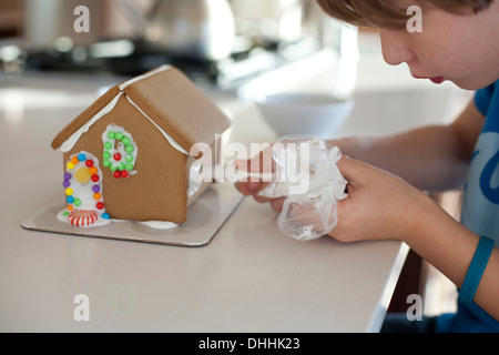 Boy decorating gingerbread house Banque D'Images