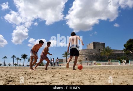 Trois adolescents jouant au football sur la plage à Castello à Manfredonia, Gargano, Pouilles, Italie Banque D'Images