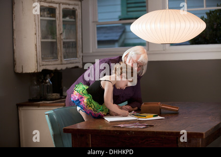 Grand-mère et sa petite-fille debout à dessin de table Banque D'Images