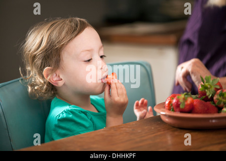 Fille assise mangeant bol de fraises Banque D'Images