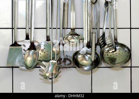 Cuisine divers louches pendants devant un mur carrelé blanc, Allemagne Banque D'Images