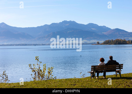 Les touristes assis sur un banc au bord du lac de Chiemsee, ou l'île de Frauenchiemsee Fraueninsel, Chiemsee, Upper Bavaria, Bavaria, Germany Banque D'Images