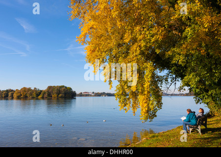 Les touristes assis sur un banc au bord du lac de Chiemsee, ou l'île de Frauenchiemsee Fraueninsel, Chiemsee, Upper Bavaria, Bavaria, Germany Banque D'Images