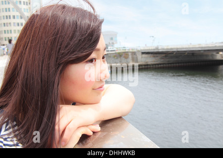 Young woman leaning on les garde-corps avec vue sur la rivière Banque D'Images