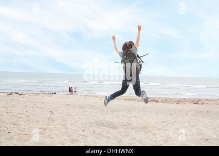 Rear view of woman jumping on beach Banque D'Images