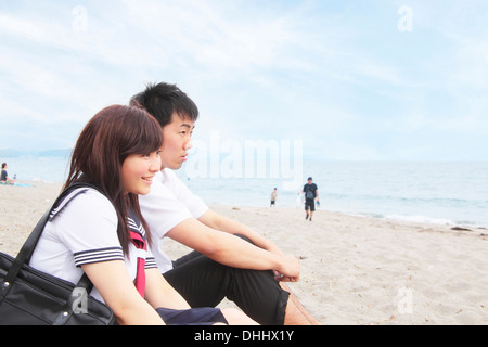 Jeune couple assis sur une plage de sable Banque D'Images