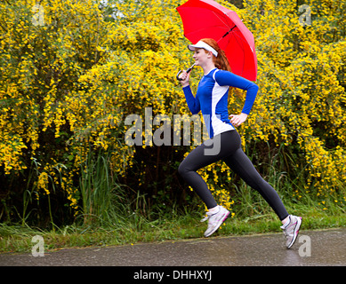 Woman jogging avec parapluie sur route, Bainbridge Island, Washington, USA Banque D'Images