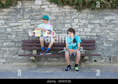 Portrait de deux garçons assis sur le banc de la holding skateboards Banque D'Images