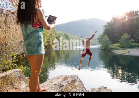Femme photographiant copain sautant d'rock ledge, Hamburg, New York, USA