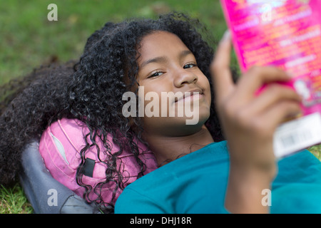 Close up portrait of young girl reading in park Banque D'Images