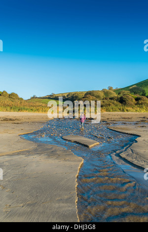Walker traversant un ruisseau sur une plage d'inondations après de fortes pluies. Wonwell, dans le sud du Devon. UK Banque D'Images