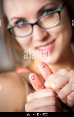 Jolie femme avec des sourires sur les pouces giving Thumbs up Banque D'Images