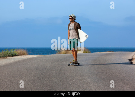 Patinage de garçon avec chapeau et his surfboard Banque D'Images