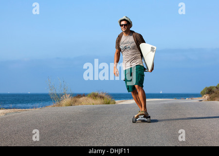 Patinage de garçon avec chapeau et his surfboard Banque D'Images