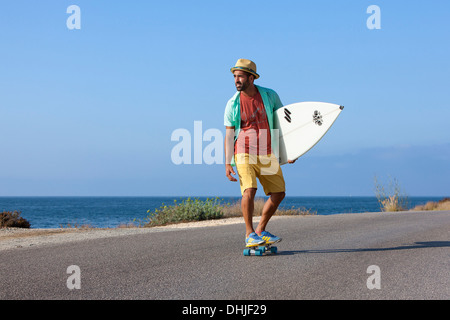 Patinage de garçon avec chapeau et his surfboard Banque D'Images