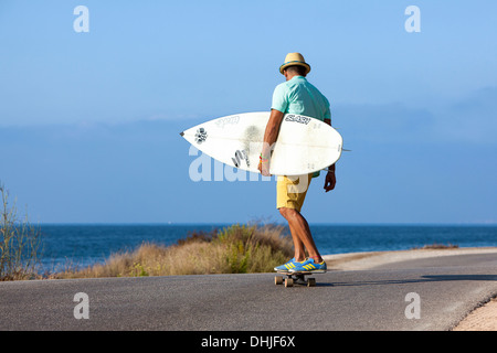 Patinage de garçon avec chapeau et his surfboard Banque D'Images