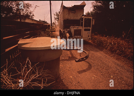 Le bras mécanique d'un camion à ordures soulève des conteneurs de 320 gallons et les vide, une démonstration de la technologie moderne de collecte des déchets en action. Banque D'Images