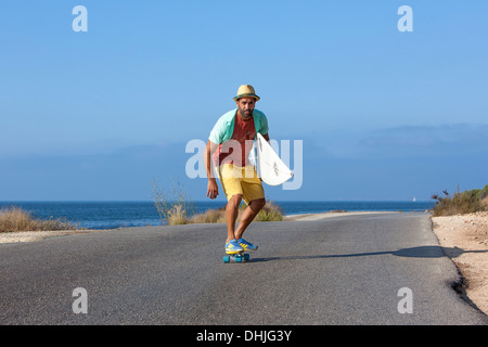 Patinage de garçon avec chapeau et his surfboard Banque D'Images