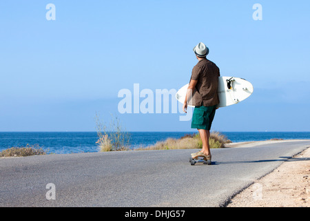 Patinage de garçon avec chapeau et his surfboard Banque D'Images