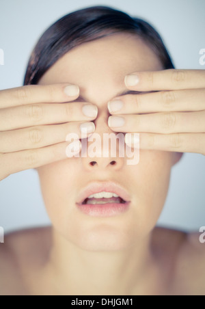 Une jeune femme couvrant ses yeux avec ses mains Banque D'Images
