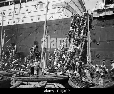 Voir des travailleurs locaux avec des paniers de charbon de soutage de junks via des échelles de corde de fortune à la trappes de chargement et à bord du paquebot de ligne 'Cleveland' dans la région de Nagasaki, Japon, autour de 1911/1913. L'image a été prise par le photographe allemand Oswald Lübeck, l'un des premiers représentants de la photographie de voyage et de photographie à bord des navires Les navires à passagers. Photo : Deutsche Fotothek/Oswald Lübeck Banque D'Images