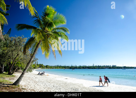 Les gens marcher sur le sable blanc parfait d'une plage tropicale, au-dessous des palmiers et à côté de la mer d'un bleu pur Banque D'Images