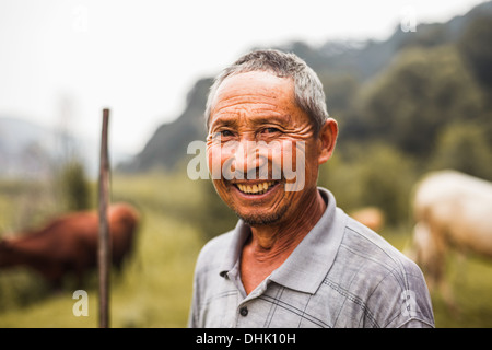 Portrait of smiling farmer avec le bétail dans l'arrière-plan, les régions rurales de la Chine, dans la province du Shanxi Banque D'Images