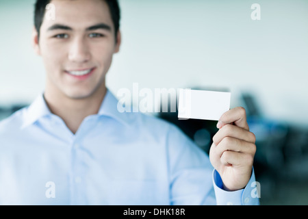 Smiling young woman holding a carte d'affaires et looking at camera Banque D'Images